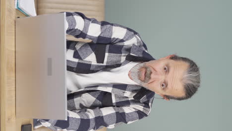 Vertical-video-of-The-old-man-who-likes-the-application-on-the-laptop-is-happy.